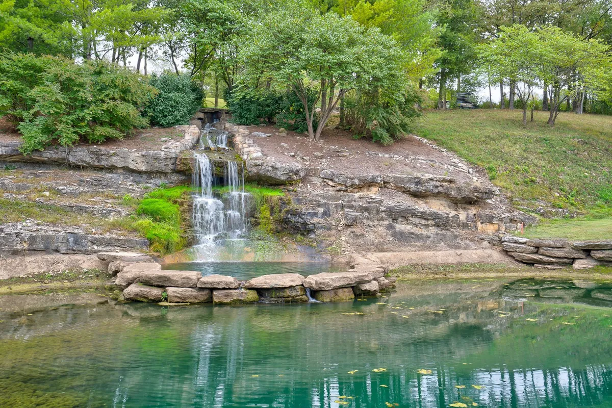 A serene catch-and-release pond set among natural rock formations and dense greenery, with a small waterfall cascading into the pond. The setting invites fishing, picnicking, and peaceful nature walks, showcasing the tranquil side of the resort's outdoor offerings.